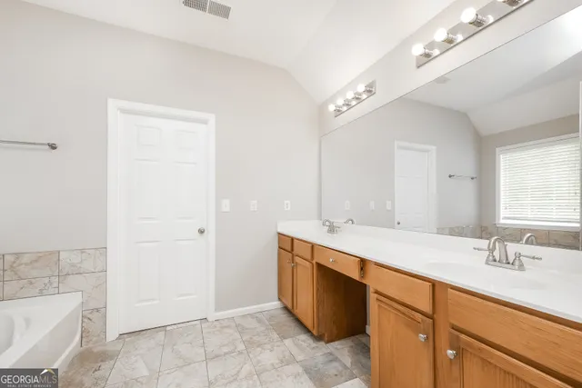 a spacious bathroom with a granite countertop sink a toilet a mirror and bathtub