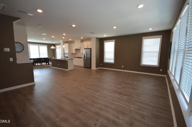 an open kitchen with refrigerator and wooden floor