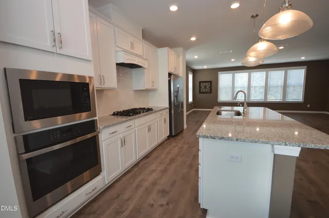 a kitchen with a stove sink and wooden floor