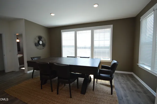 a open kitchen with stainless steel appliances granite countertop a stove top oven a sink dishwasher a dining table and chairs with wooden floor