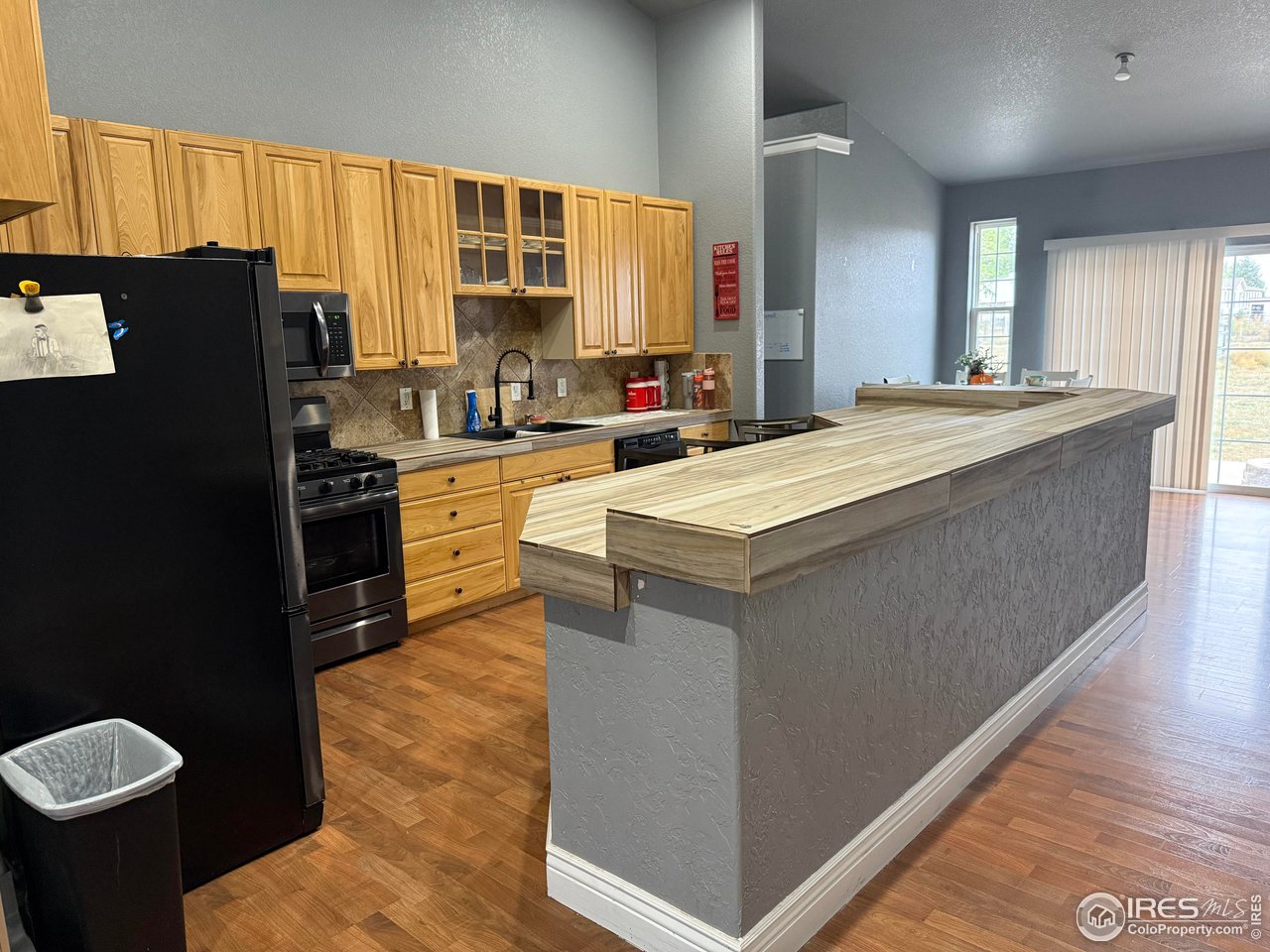 419 East 3rd Avenue Wiggins, CO 80654 - Photo 6 of 20 a large kitchen with kitchen island granite countertop wooden cabinets a refrigerator and a sink