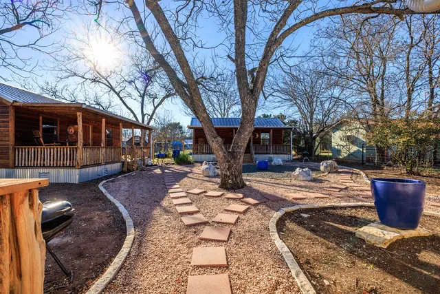 a view of a backyard with table and chairs potted plants and large tree
