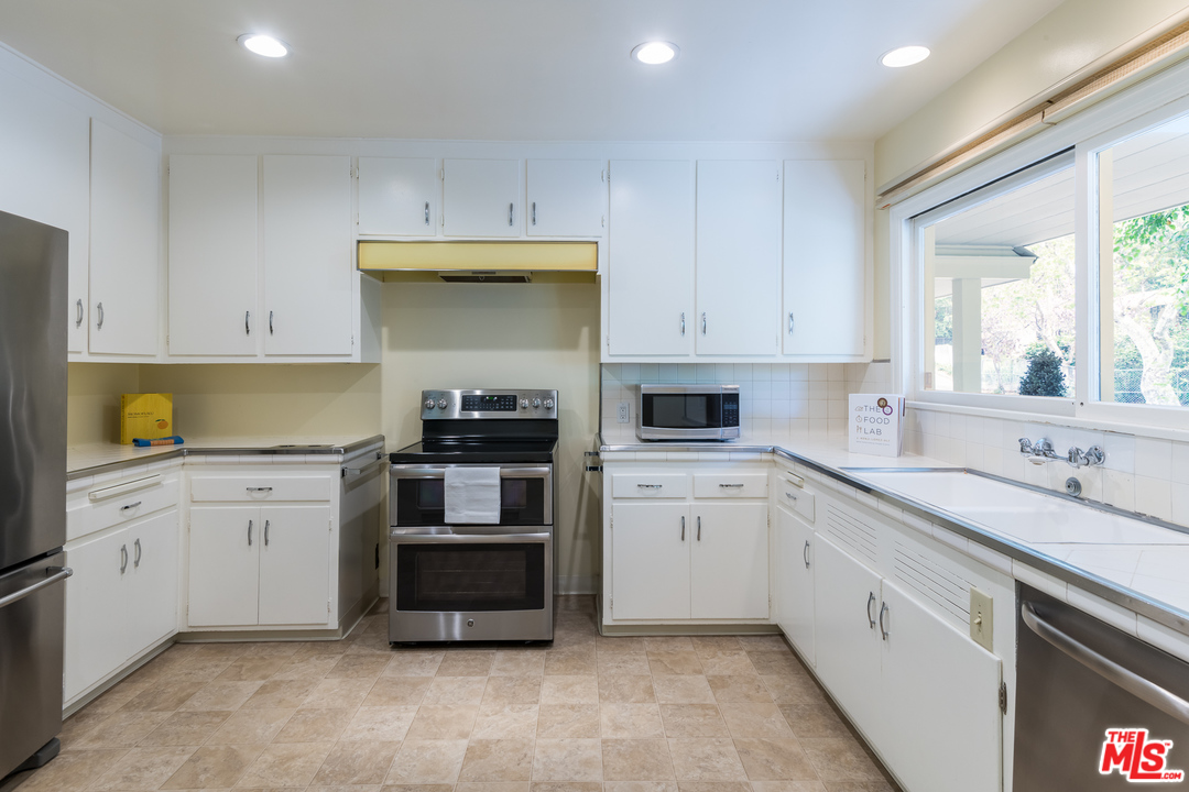 10886 Chalon Road Los Angeles, CA 90077 - Photo 13 of 33 a kitchen with granite countertop white cabinets and stainless steel appliances