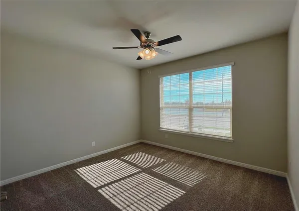 an empty room with windows and ceiling fan
