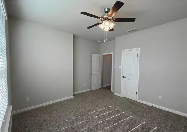 an empty room with a chandelier fan and windows