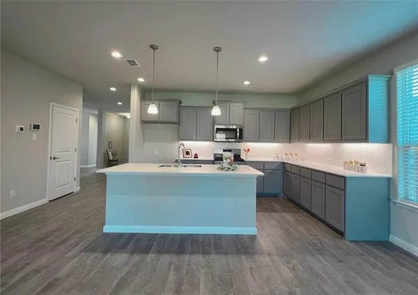 a large kitchen with stainless steel appliances granite countertop a large counter top a sink and a refrigerator