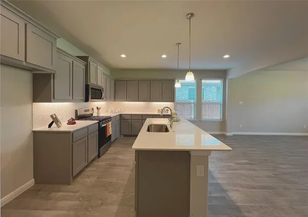 a large kitchen with kitchen island a sink dishwasher stove with wooden cabinets and floor