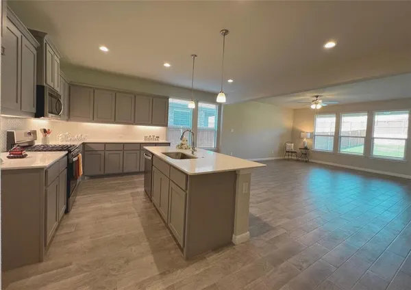 a large kitchen with a large counter top a sink a window and stainless steel appliances