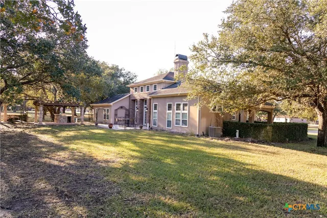a front view of a house with a yard and large trees