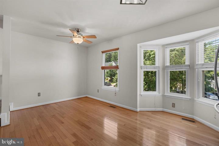 1163 Kelfield Drive, Unit 1163 Baltimore, MD 21227 - Photo 11 of 28 an empty room with wooden floor ceiling fan and windows