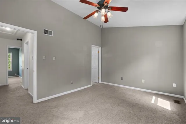 a view of an empty room and chandelier fan