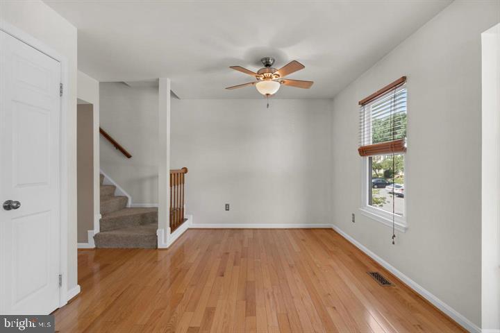 1163 Kelfield Drive, Unit 1163 Baltimore, MD 21227 - Photo 10 of 28 an empty room with wooden floor chandelier fan and windows