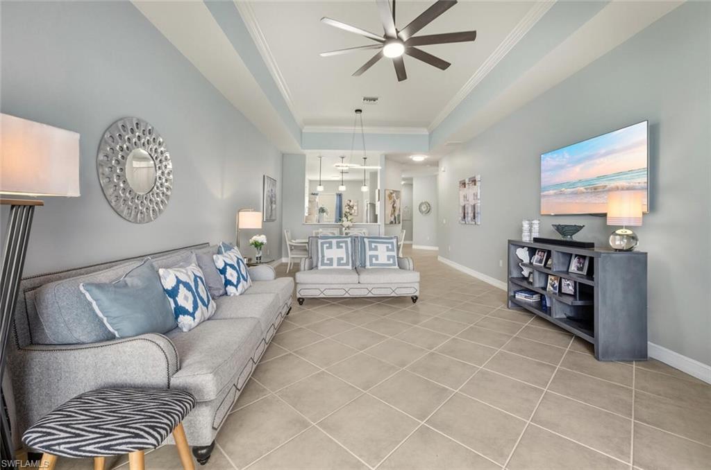 8063 Sanctuary Drive, Unit 1 Naples, FL 34104 - Photo 13 of 30 Living room with ornamental molding, light tile patterned floors, a raised ceiling, and a ceiling fan