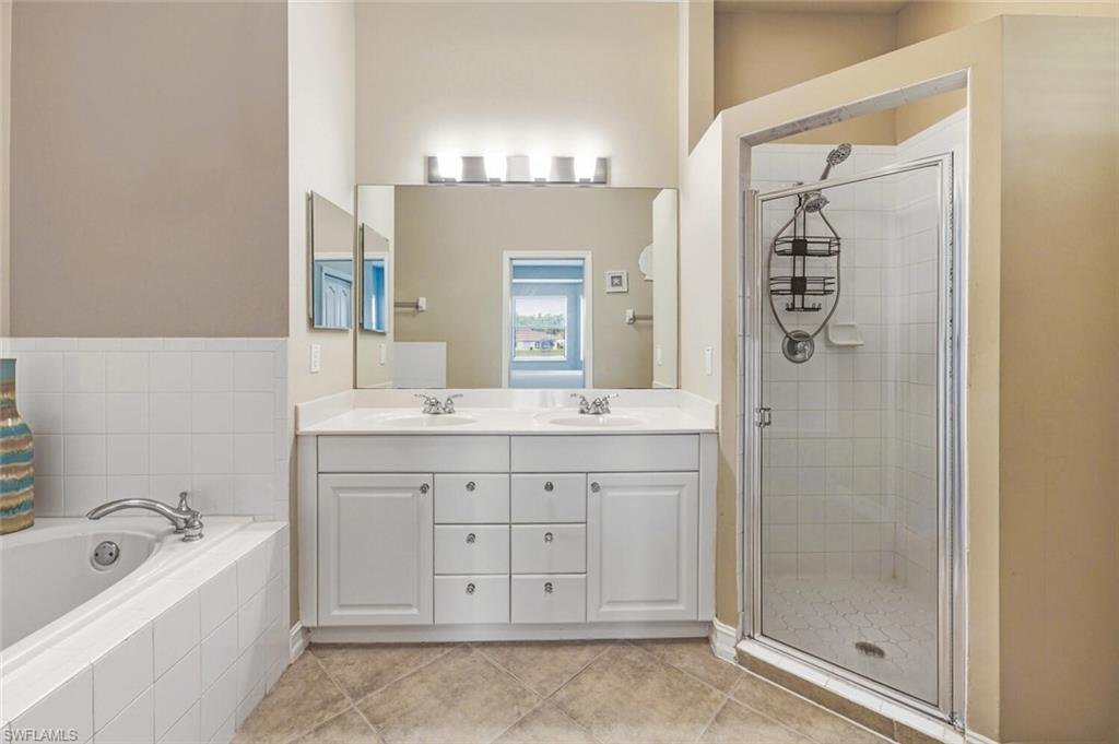 8063 Sanctuary Drive, Unit 1 Naples, FL 34104 - Photo 25 of 30 Full bath with double vanity, a stall shower, light tile patterned floors, and a garden tub