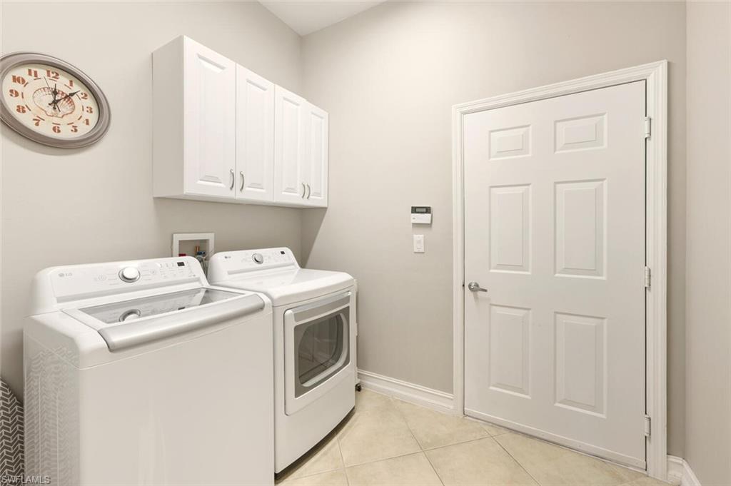 8063 Sanctuary Drive, Unit 1 Naples, FL 34104 - Photo 26 of 30 Laundry area with light tile patterned floors, cabinet space, and washer and dryer