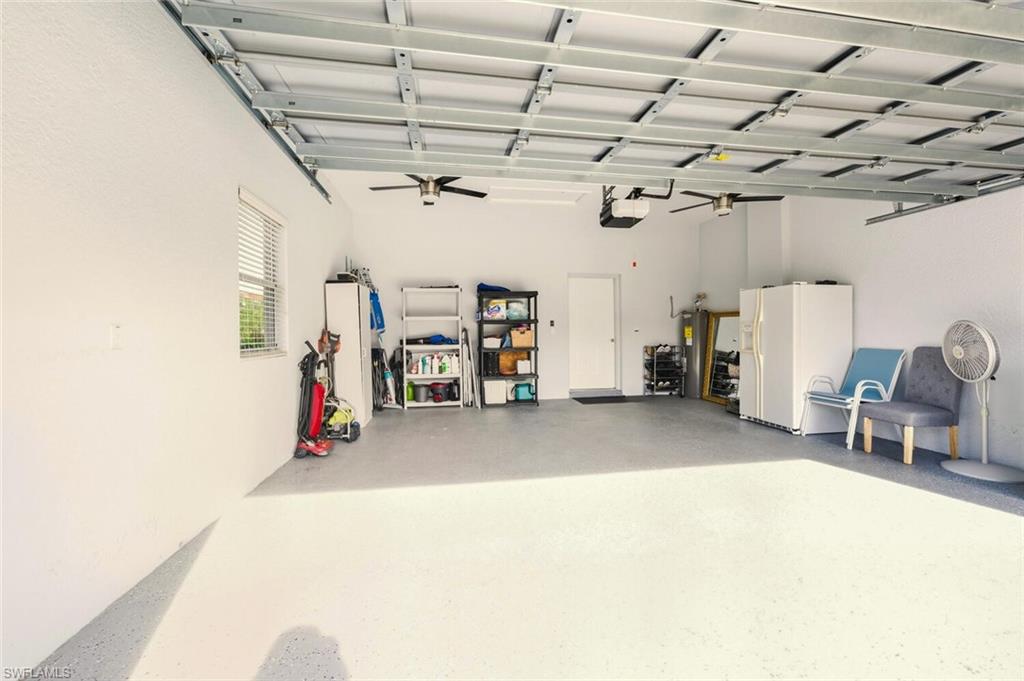 8063 Sanctuary Drive, Unit 1 Naples, FL 34104 - Photo 27 of 30 Garage with white fridge with ice dispenser, electric water heater, and a garage door opener