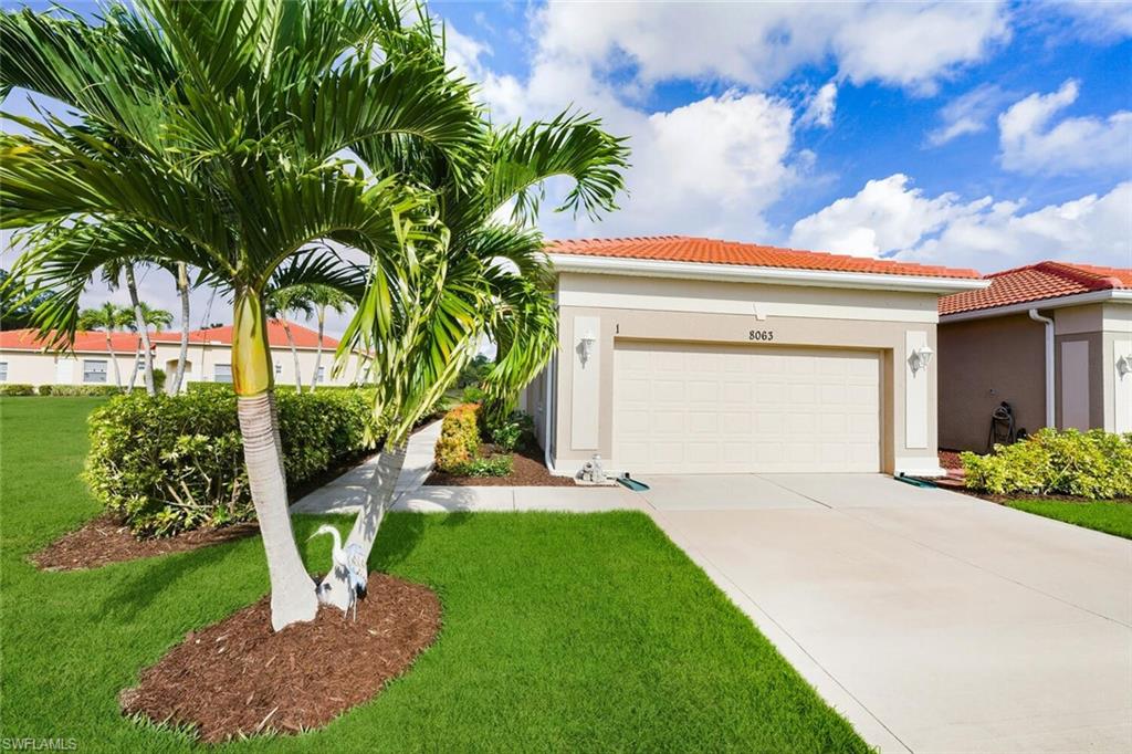 8063 Sanctuary Drive, Unit 1 Naples, FL 34104 - Photo 5 of 30 View of front facade featuring a tiled roof, stucco siding, driveway, and a front yard