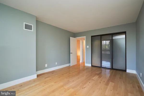 a view of an empty room with wooden floor and closet