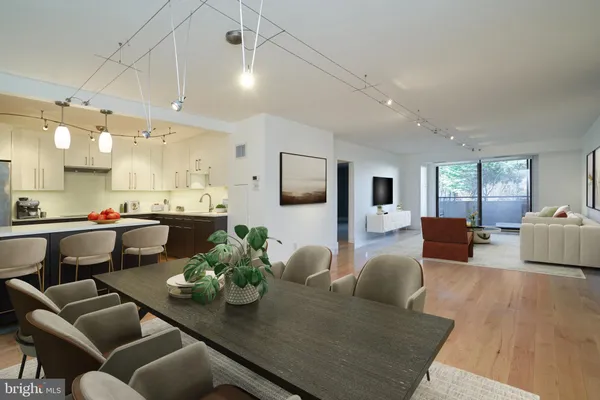 a living room with furniture kitchen view and a wooden floor