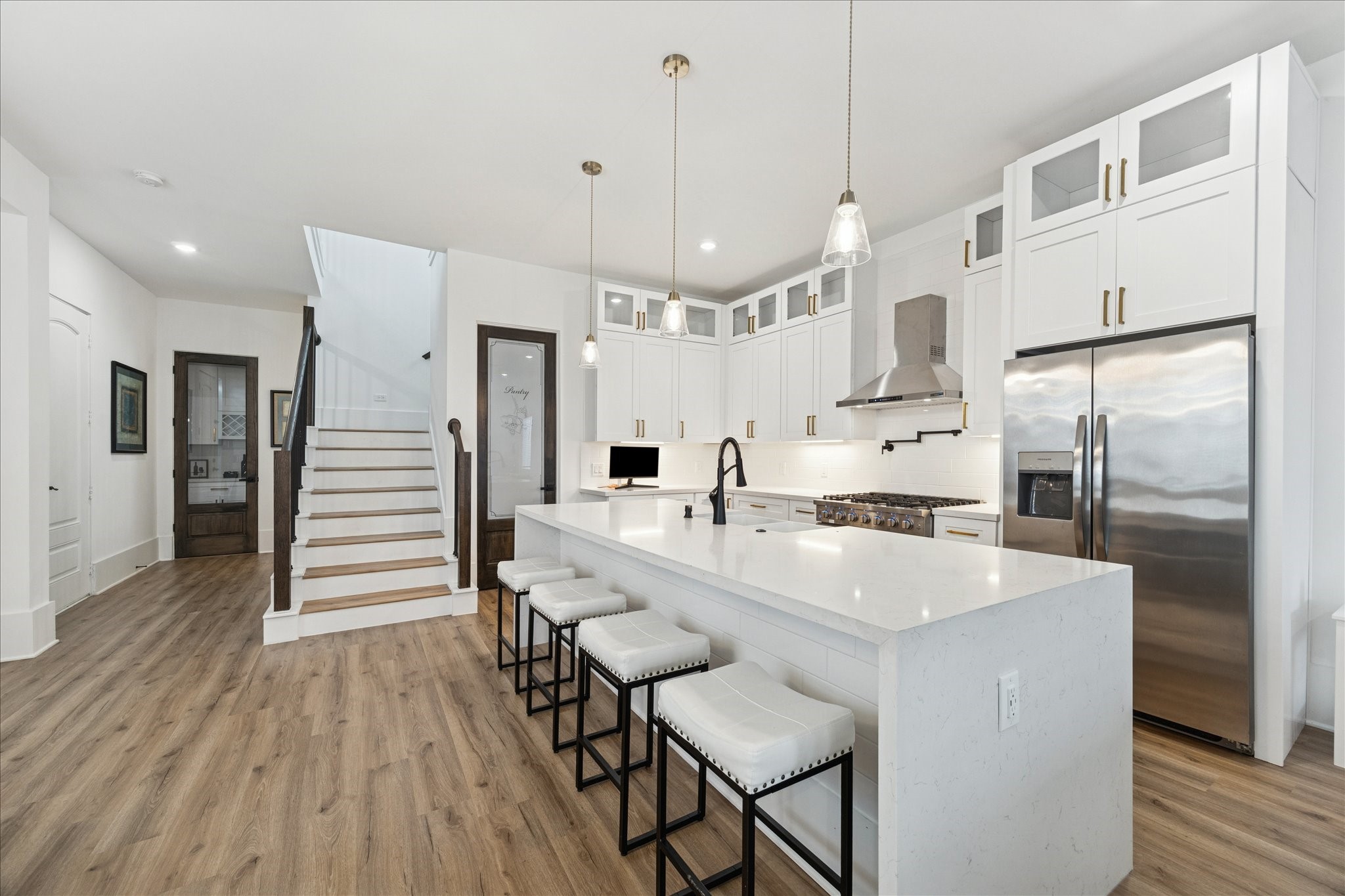 9233 Madera Road Houston, TX 77078 - Photo 10 of 25 a large kitchen with white cabinets stainless steel appliances and wooden floor