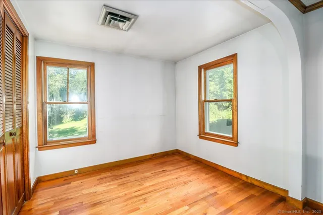 an empty room with wooden floor and windows
