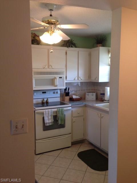 4338 27th Court Southwest, Unit 8201 Naples, FL 34116 - Photo 3 of 19 a kitchen with stainless steel appliances granite countertop a sink stove and cabinets