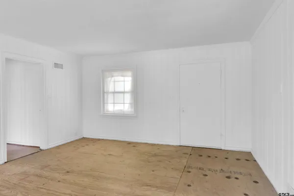 an empty room with wooden floor chandelier and windows