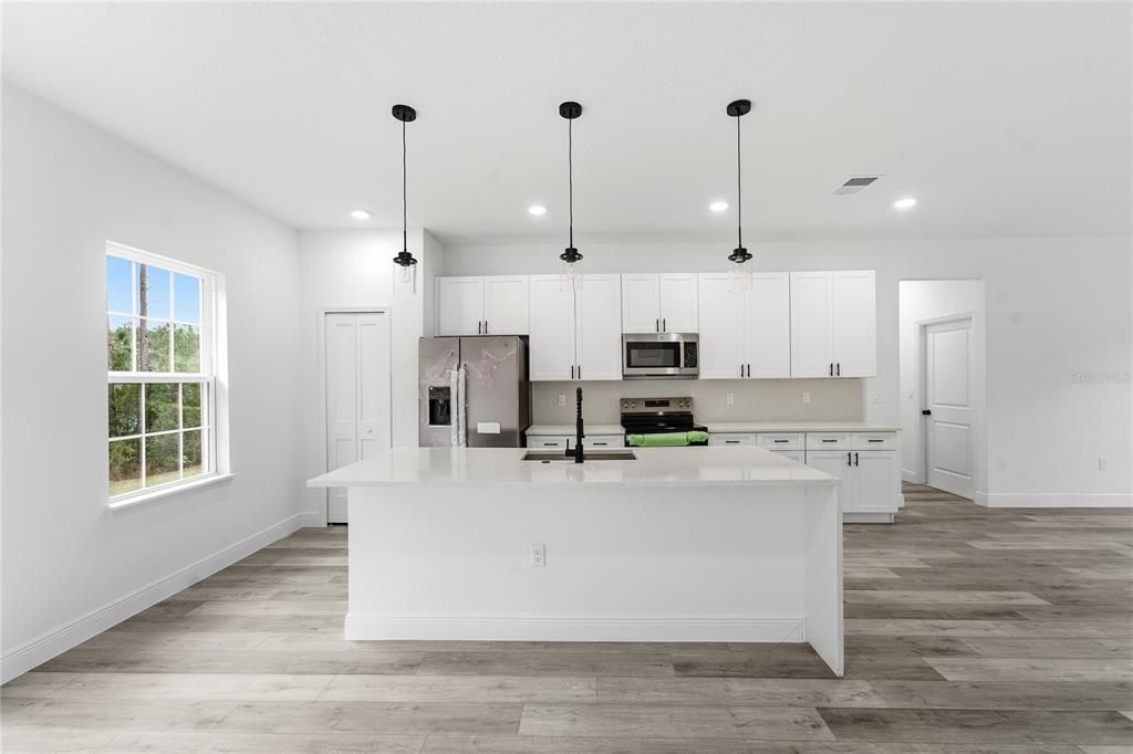 2773 Southwest 147st Street Road Ocala, FL 34473 - Photo 12 of 35 a large kitchen with stainless steel appliances kitchen island a large counter top and a wooden floors
