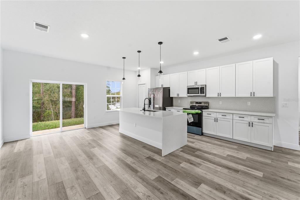 2773 Southwest 147st Street Road Ocala, FL 34473 - Photo 5 of 35 a large white kitchen with kitchen island a sink a center island stainless steel appliances and a cabinets