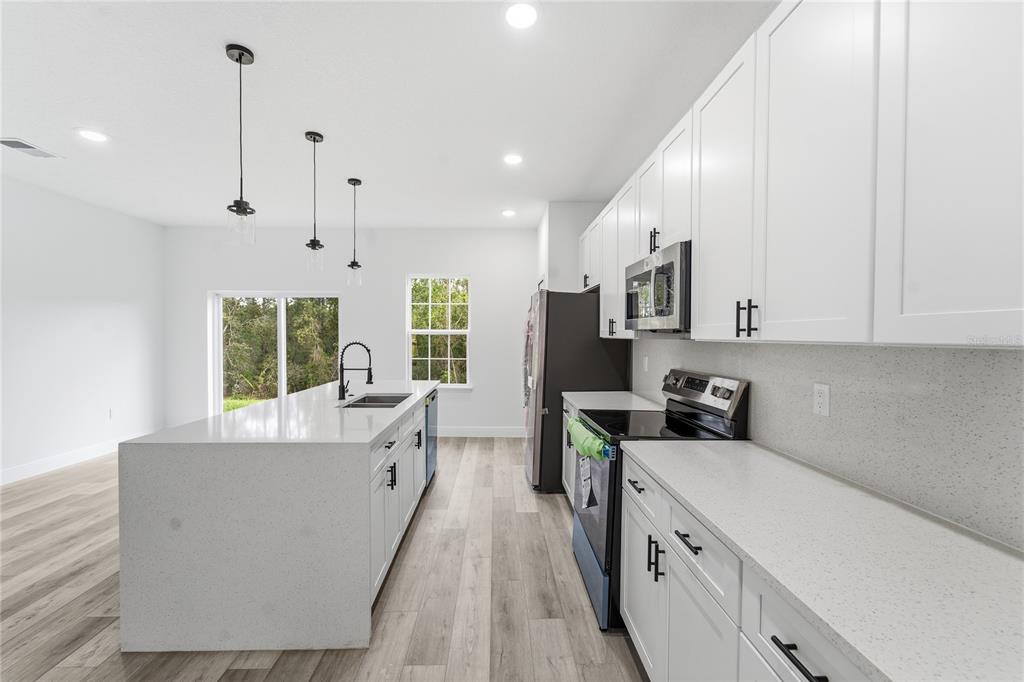 2773 Southwest 147st Street Road Ocala, FL 34473 - Photo 10 of 35 a large kitchen with stainless steel appliances granite countertop a lot of counter space and wooden floor