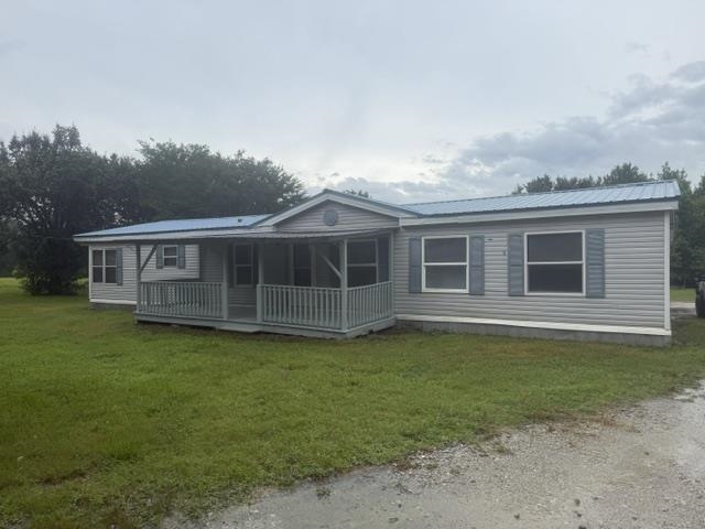 1100 Pine Top Road Toone, TN 38381 - Photo 3 of 40 Gray siding exterior with a blue metal roof, front porch, and decorative window shutters