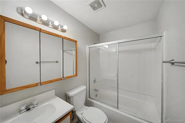 a bathroom with a shower sink vanity mirror and toilet
