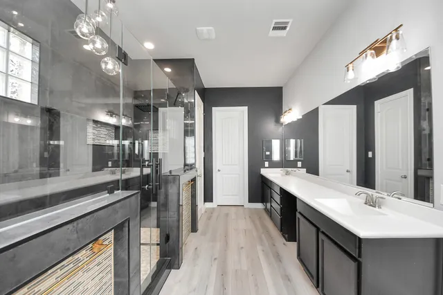 a large kitchen with a large counter top a sink stainless steel appliances and cabinets