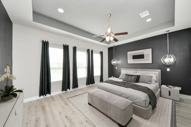 a view of an empty room with wooden floor and fan