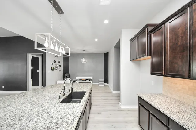 a kitchen with granite countertop a refrigerator a stove and a sink