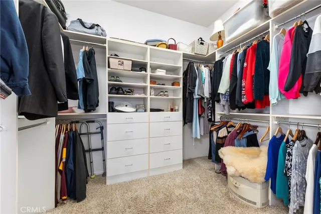 a view of walk in closet with clothes and shoes