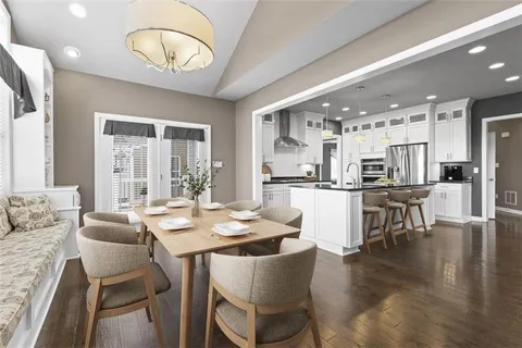 a kitchen with stainless steel appliances kitchen island granite countertop a table and chairs in it
