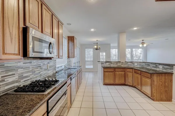 a kitchen with stainless steel appliances granite countertop a stove a sink and a microwave