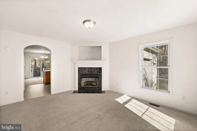 an empty room with windows and fireplace