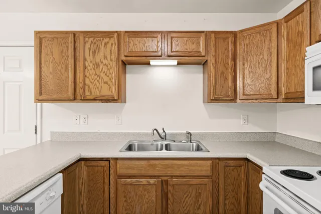 a kitchen with stainless steel appliances granite countertop a sink dishwasher a stove and white cabinets with wooden floor