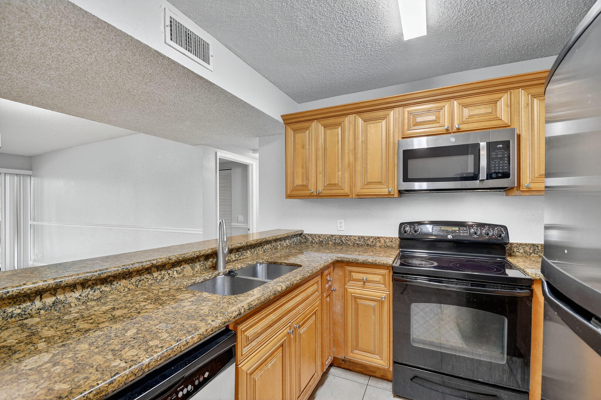 1601 Windorah Way, Unit D West Palm Beach, FL 33411 - Photo 26 of 41 a kitchen with stainless steel appliances granite countertop a sink a stove a microwave and wooden cabinets
