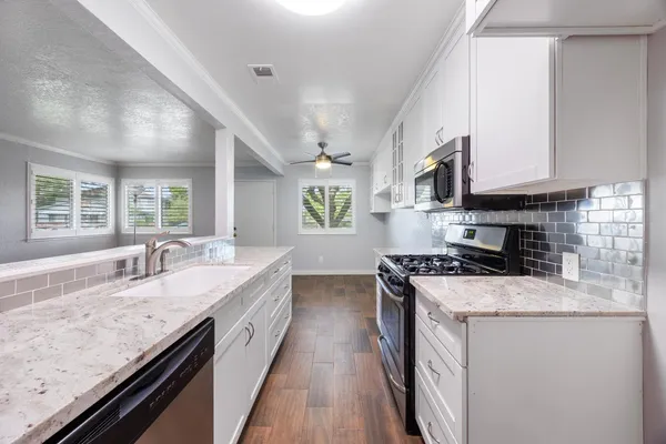 a kitchen with granite countertop stainless steel appliances a sink a stove cabinets counter space and a window