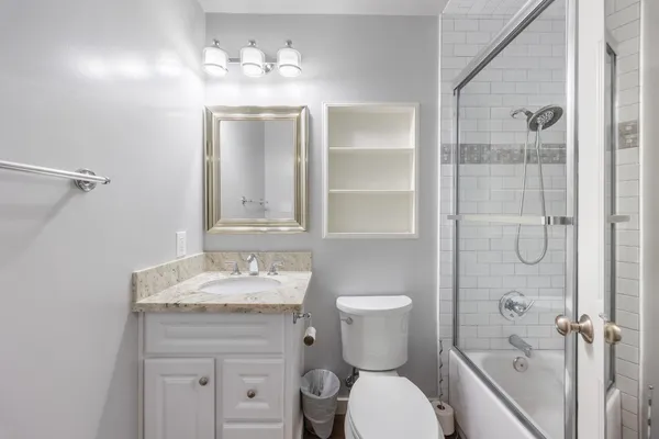 a bathroom with a granite countertop sink toilet a mirror and shower