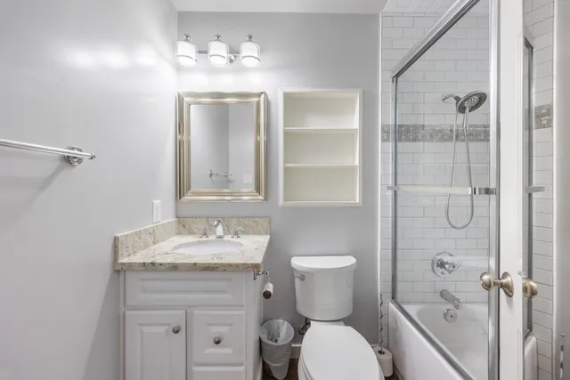 a bathroom with a granite countertop sink toilet a mirror and shower