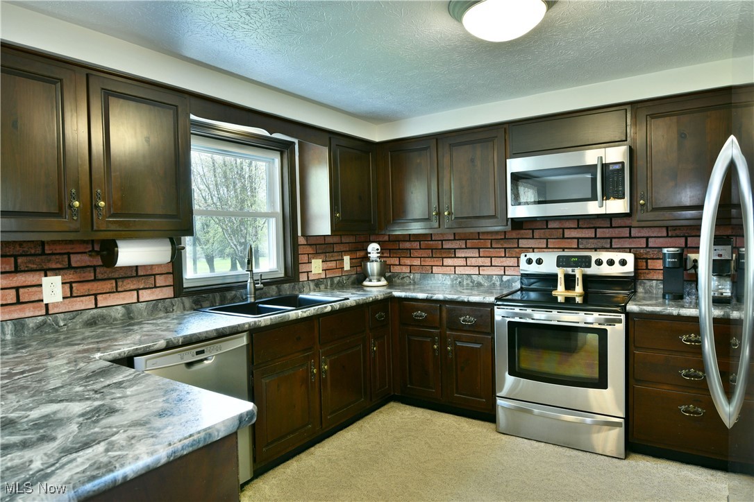 379 Housel Craft Road Bristolville, OH 44402 - Photo 11 of 50 Kitchen with a sink, stainless steel appliances, and dark brown cabinets