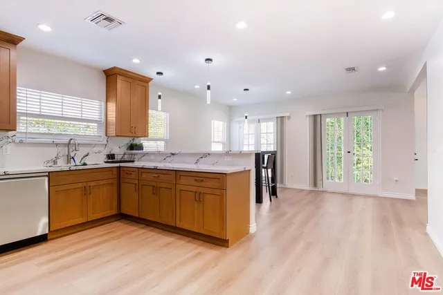 a large kitchen with stainless steel appliances granite countertop a large center island a sink dishwasher and a large refrigerator with wooden floor