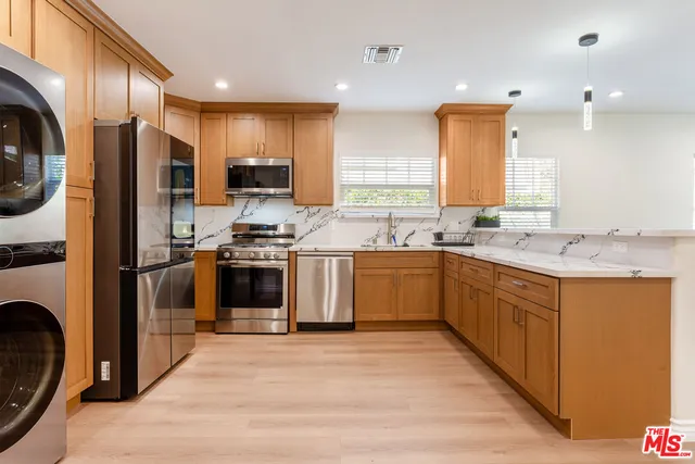 a kitchen with stainless steel appliances granite countertop a stove a sink and a refrigerator