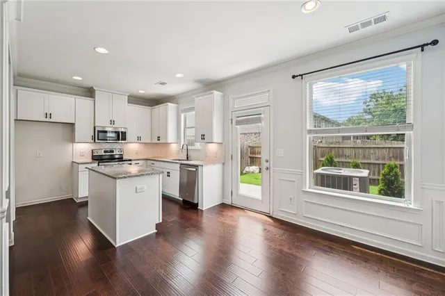 a kitchen with stainless steel appliances granite countertop wooden cabinets a stove a sink and a refrigerator