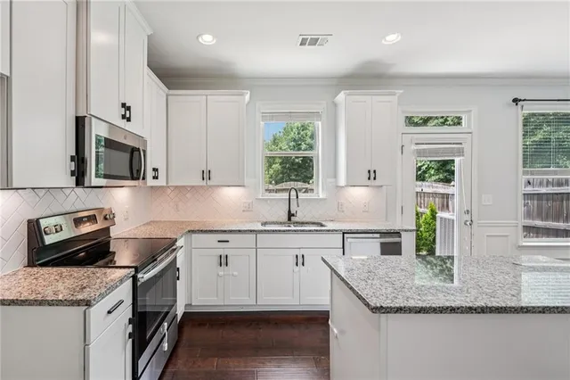 a kitchen with granite countertop a sink dishwasher stove and cabinets