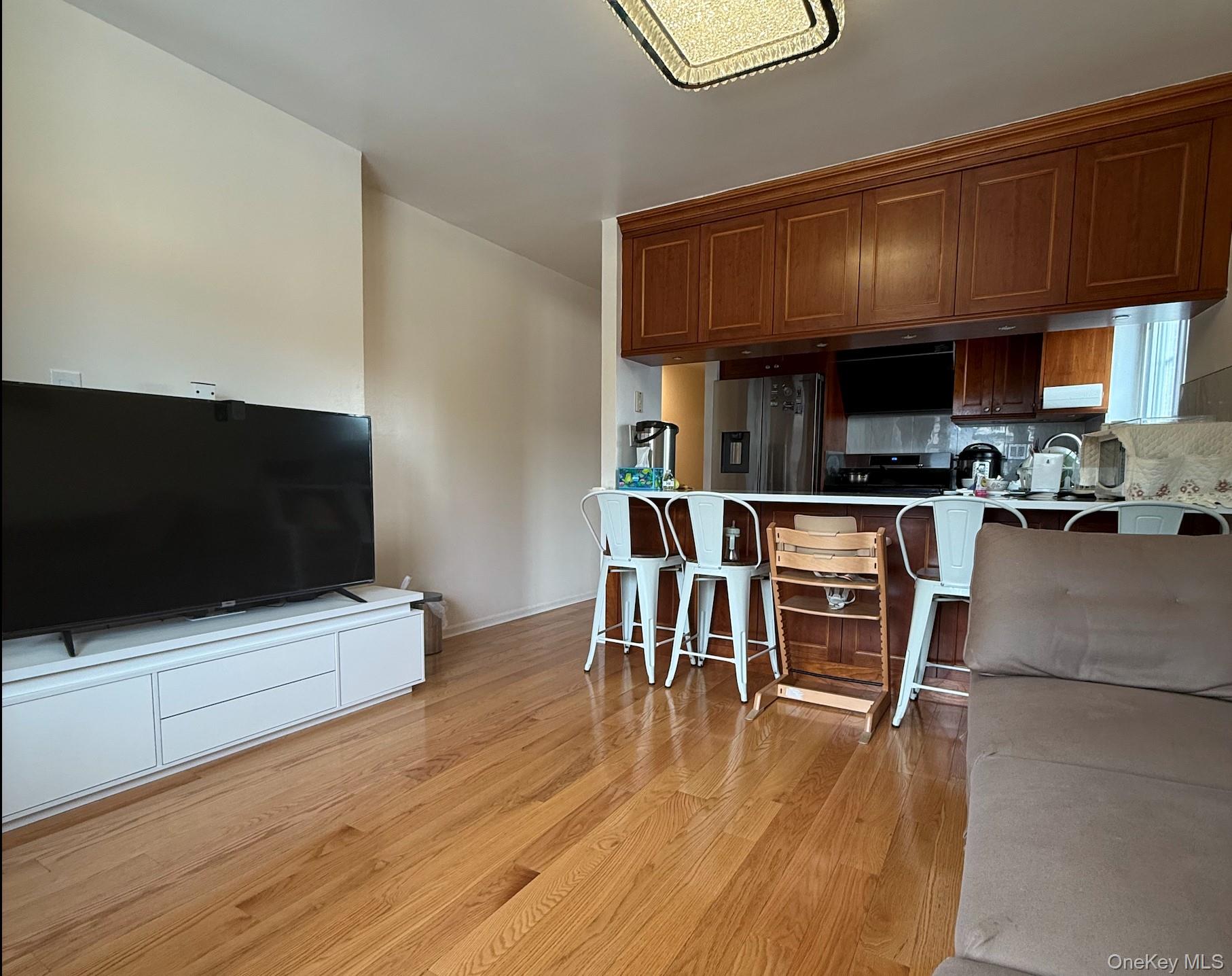 43-24 163rd Street Queens, NY 11358 - Photo 2 of 12 Kitchen featuring a kitchen bar, light wood finished floors, stainless steel fridge with ice dispenser, decorative backsplash, and light countertops